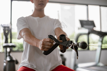 练习有氧运动训体操概念一名男少年使用体操设备将两只肌肉手臂对着机器拉来去运动图片