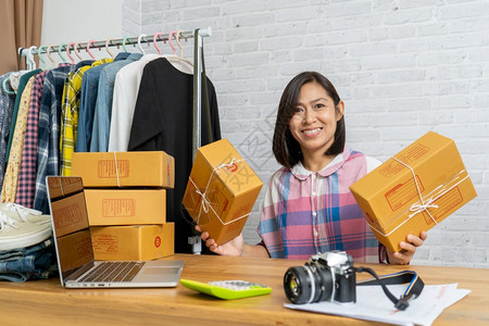 办公室中小企业亚洲妇女创办了拥有包装纸箱电子商务思想概念的小企业主亚洲妇女卖方图片