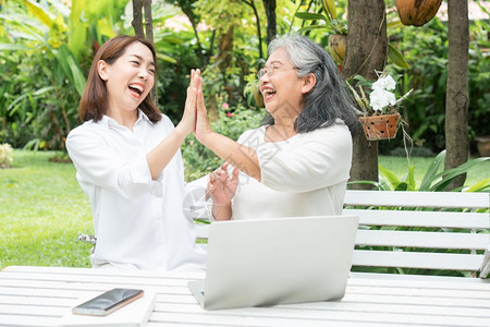 退休后学习技术概念和老年人适应改造亚洲女儿教育年长妇使用计算机笔记本电脑手提在线社交媒体教授年长老妇女的亚洲儿在线快乐年长图片