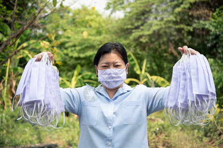 室外手拿防护口罩的女性图片