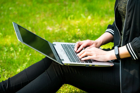 键盘个人电脑网络一名妇女使用笔记本电脑坐在草地上图片