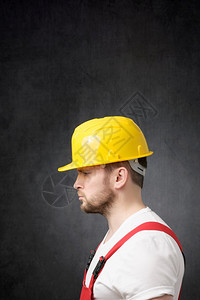 一边看眼个沮丧的建筑工人带着黄色硬帽子悲伤的建筑工人男无聊的专业图片