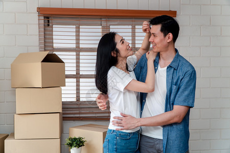 包装买下新婚夫妇开始生活的概念在购买新家后搬来的路上用纸板盒拥抱男友时使用纸板盒拥抱着男朋友的年轻亚洲快乐情侣微笑为了人们图片
