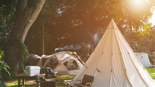 自然公园地带露营区的野帐篷组和配有户外厨房设备的木制桌板露台图片