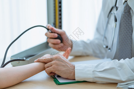 医生用两只手指检查一名女病人手腕的脉搏用医院疗和概念中的汞血压与水银计进行检查医生用两只手指检查一位女病人手腕的脉搏和验血压力帮背景图片