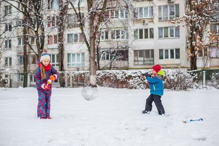 脸快乐的兄弟姐妹在冬季散步时打雪球在公园里做雪球冬季户外游戏快乐的兄弟姐妹在冬季散步时玩雪球在公园里做雪球美丽的手套图片