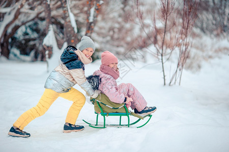 可爱的小女孩享受雪橇滑孩子们在地游和户外玩戏在圣诞节前夕家庭渡假圣诞晚夜露户外可喜的小快乐女孩在冬季雪天滑节女孩们动图片
