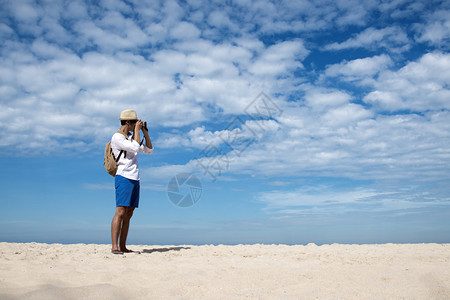 年轻男子在热带海滩上旅行拍照图片