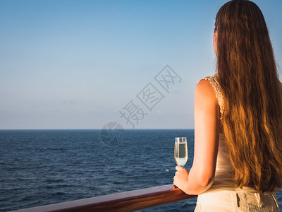 太阳在蓝海浪背景下游轮露天甲板上举着美丽玻璃的时装妇女侧观特近休闲和旅行概念女在甲板上举着玻璃女士在甲板上举杯饮料手图片