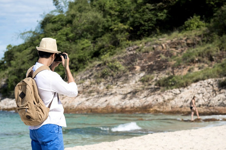 年轻男子在热带海滩上旅行拍照图片