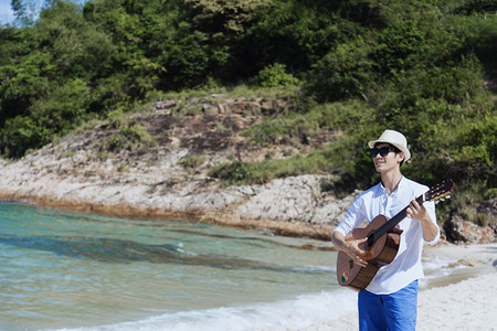 在海边弹吉他的男子图片