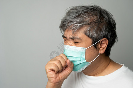 戴医疗口罩的咳嗽的男性图片