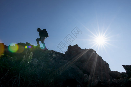 一个年轻的背包男在一个明亮的日光照耀着美丽的阳光下徒步旅行登山攀岩一个者轮廓风景日落图片