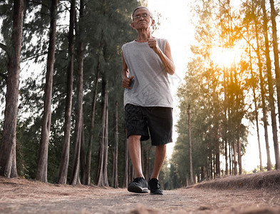 训练亚洲高年长男子在日落天空背景的公园里慢跑健康生活方式和保健概念户外老年图片