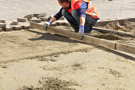 板坯根据在人行道上工将沙台与木板对齐准备铺设路板的基础工人将沙与木板对齐用于在人行道上铺设路板材料图片