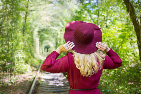穿着樱桃洋装的漂亮女孩在树林里戴帽子紧贴在树林里戴着帽子的漂亮女孩落下十月美丽图片