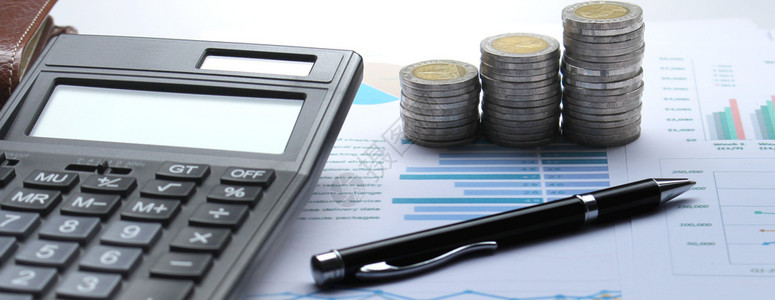 国际的会计算器硬币堆积财务图表和办公桌上的笔背景股票图报告图片