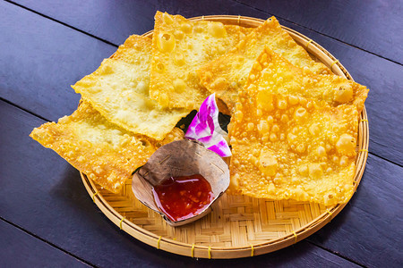 健康黄炸面包子和竹菜上一碗酱汁装饰在桌边黑木的兰花上热亚洲图片