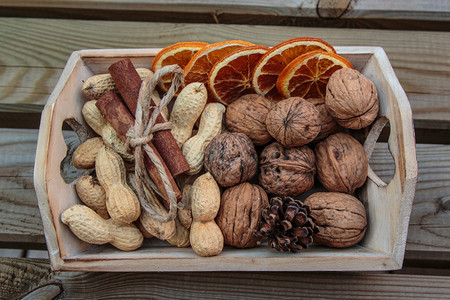 带胡桃花生种子肉桂棒和脱水橙虱子的小木箱水果丰富饮食图片
