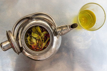 可口茶壶草药在不锈钢板上加杯热草药茶健康作品图片