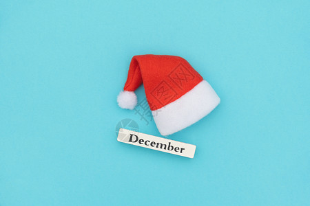 布局Wooden日历12月冬季红色闹钟和蓝纸背景的圣诞老人帽Xmas或新年创意顶见像FlatLayWooden日历冬月12季Sa图片