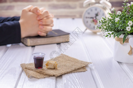服用年轻妇女祷告和圣餐经复活节逾越和晚餐领主概念的基督血液和身体的葡萄酒面包象征以她的玻璃为焦点语料库图片