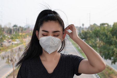 脸女士一名黑人衬衫女站在穿戴呼吸器N95防毒面具的黑衬衫女面前以保护免受空气呼吸道疾病的影响因为甲型流感在路上染布满了本底的PM图片