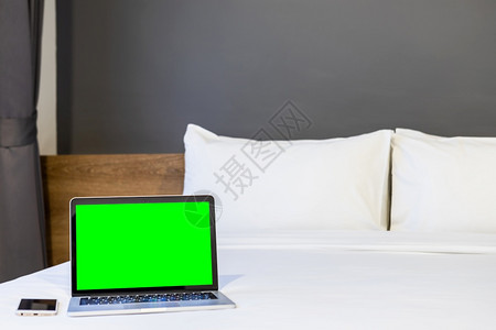 放松在旅馆卧室内背景工作和业余休闲以及度假旅行概念下的中带绿色屏幕和智能手机的提电脑在白色床上装饰的酒店卧室内衣工作和商业假期家图片