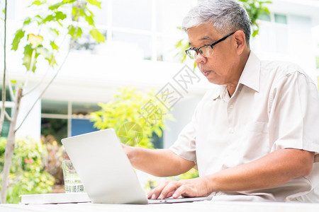 技术拉紧利用后院的电脑笔记本在退休无年龄歧视概念之后学习新技能不晚于学习时间的亚洲老年人肖像男图片