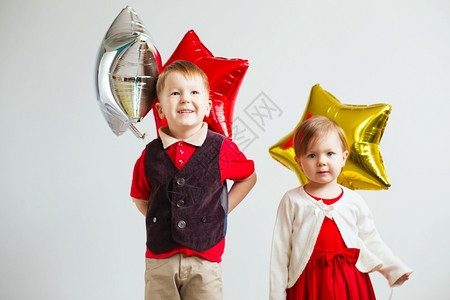 金子明亮的生日带着恒星形气球的儿童快乐在白色背景下玩着多彩亮闪发光的浮雕气球图片