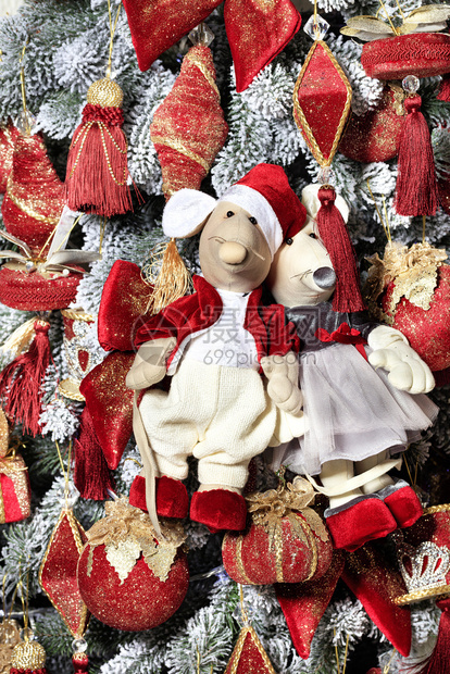 穿着红大衣和优雅礼服的装饰玩具小老鼠在大公年新庆祝活动前夕挂在圣诞树上新年庆祝概念在大公年前夕新树的背景下穿着红色衣服的装饰玩具图片