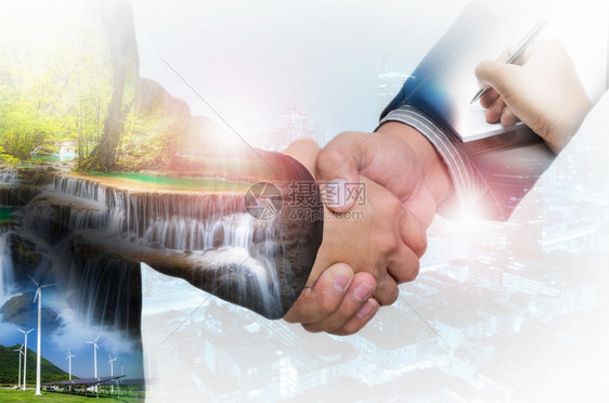 创新一名商人在深夜生活市区模糊的背景上进行双重握手接触一项协议的绿色能源商人握手概念一份协议的绿色能源商人握手可持续的成功图片