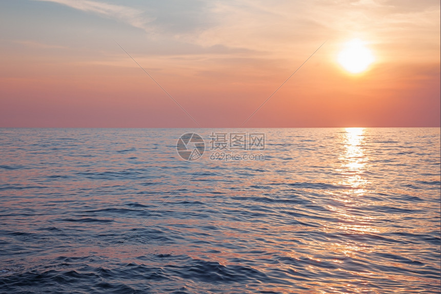 粉色的目地云日出或落在平静的海面上图片