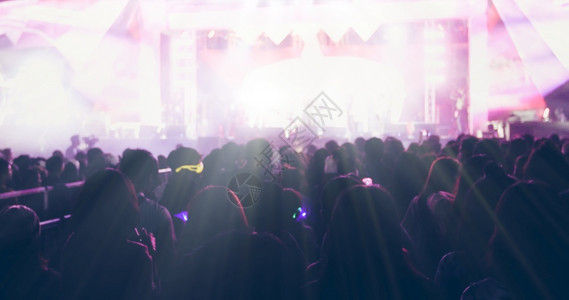 舞蹈提高明亮的台灯下举起手来在音乐会观众看节日人群的后视线上夜店图片
