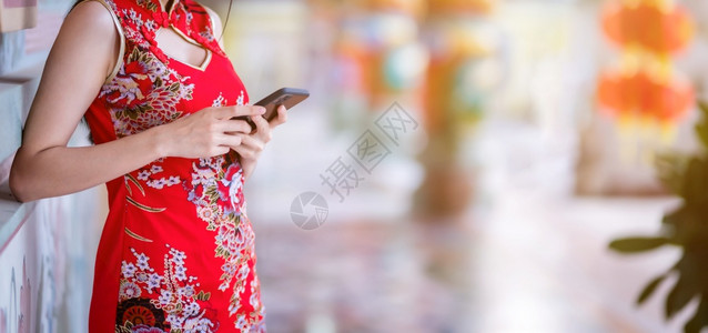 身着红色传统青山装饰的紧贴亚裔年轻女子在泰国华神庙新年节中写文智能手机贺词i支付保持成人图片