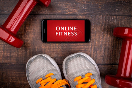 一种活动在室内用于培训在线健身课程的红运动鞋色哑铃和用木柴背景智能手机App家庭在线锻炼TopViewCovid19Corona背景图片