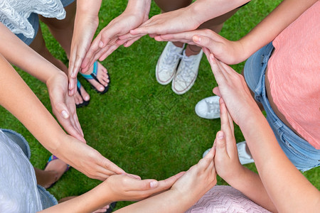社会的结合许多年轻女孩的手臂在绿草上环绕一圈团队合作图片
