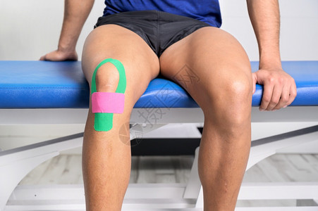 动效粘合剂嬉戏的程序年轻运动型男员用型胶带治疗受伤的膝盖特写运动学物理疗法康复概念背景