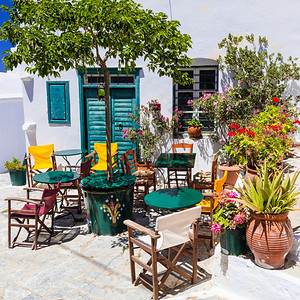 屋花的米科诺斯传统古希腊酒吧和带有典型木制椅子的塔文图片