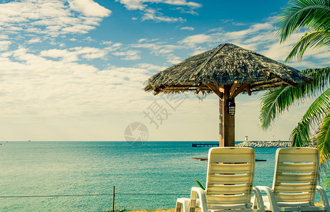 爱热带海滩风景沙椅和海边滩上阳伞的热带海滩景观阳光明媚晴朗的一天是清凉水度假胜地有码头背景下一个树图片