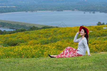 广告红色的身着自然花美丽女子她穿着白色礼服和红帽子在泰国兰芒省MaeMohCoalMine的TungBuaTong墨西哥向日葵田图片