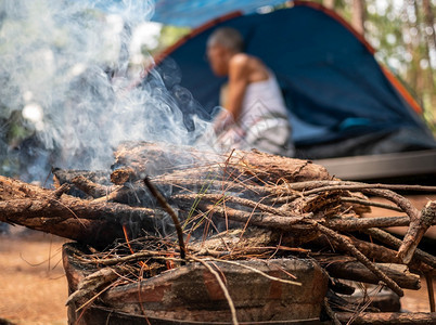 在老泰国传统炉灶中用木柴在营地的亚裔家庭在一个松树林露营点用烟雾在老泰国传统炉灶中烧柴老的活力野餐图片
