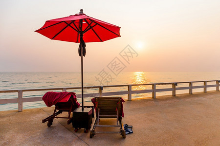 日出时红伞和游泳椅环绕户外池甲板红色的花园图片