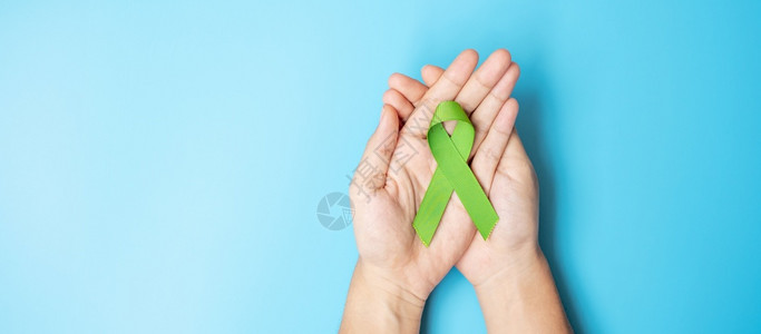 预防癌症9月世界淋巴瘤和10月世界淋巴虫和10月精神卫生日意识月在蓝色背景上以石灰绿色丝带颜支持人们生活的妇女以及疾病保健概念二月女士人背景