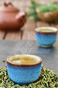 箱蓝茶碗中的热青石桌蒸汽从碗中冒出来茶叶在杯子旁边的树叶菜单最小图片