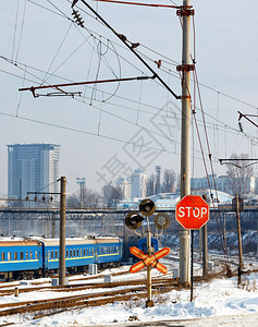 象征天空移动铁路道口的红色停车标志以铁路轨道蓝色火车厢和城市入口处的景观为背冬季城市观垂直图像城市入口处铁路道的红色停车标志以冬图片
