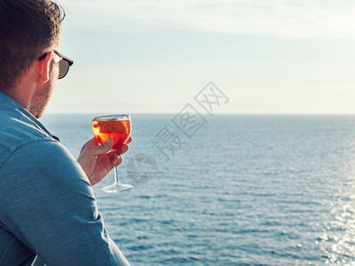成人美丽的玻璃在海浪和日光照射的背景上加一杯饮料接近的休闲概念和旅行美丽的玻璃在海洋背景上加一杯饮料水晶蓝色的图片