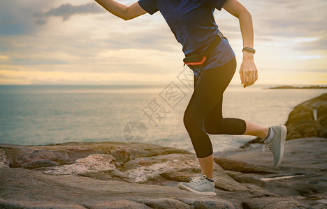 早上在海边的石滩奔跑女者与日出和健康的女人在户外锻炼健身女孩穿智能乐队和腰包女子跑去做心操跟踪器天空经过图片