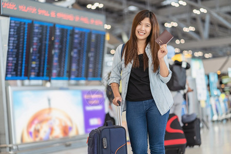 在现代机场飞行信息屏幕上登机旅行和具有技术概念的运输等现代机场旅行和运输时有护照的亚洲旅行者在飞板上站立着检查行李的肖像木板团体图片