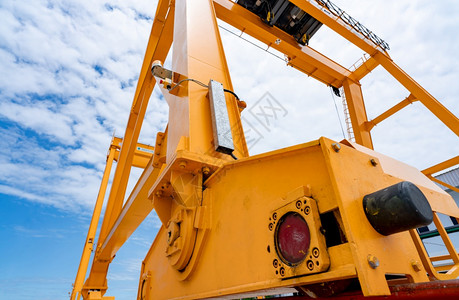 在Gantry起重机上对蓝天的黄色袋式起重机底部景色甘特利起重机用于货物和建筑行业装运重物的顶起机为了安全移动的图片